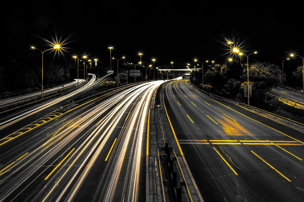 Snelweg bij nacht met lichtsporen van voorbijrijdend verkeer
