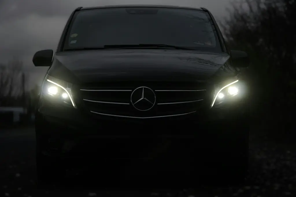 Voorkant van een zwarte Mercedes-van met brandende koplampen